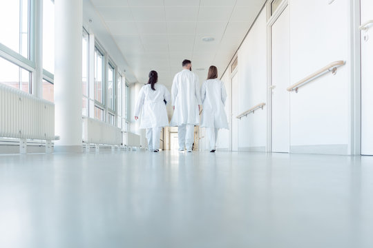 Three doctors walking down a corridor in hospital - Powered by Adobe