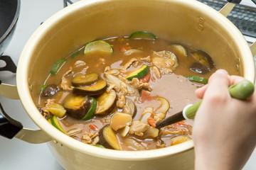 キッチンのコンロで大きい鍋で夏野菜でカレーを作っている