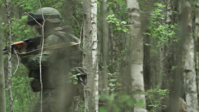 Patrol soldiers in camouflage with assault rifle walking through the forest, military action in the woods, special forces group.