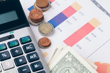 pile of money coins with graph paper on wood table, concept in account, finance and growth of business