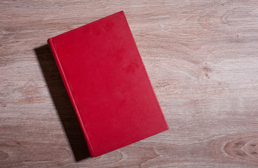 Red book on wooden background Top view