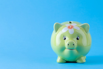 Green pig money box on a bright blue background. Finance, savings, money. space for text