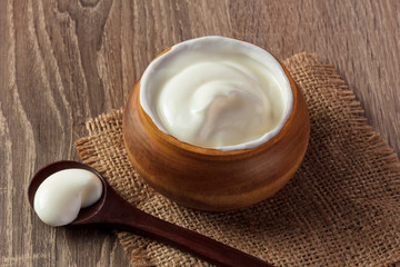 cream sour in a plate on wooden backround