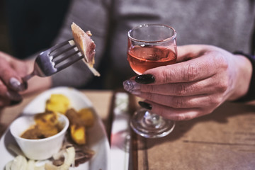 a piece of herring on a fork and a glass with alcohol