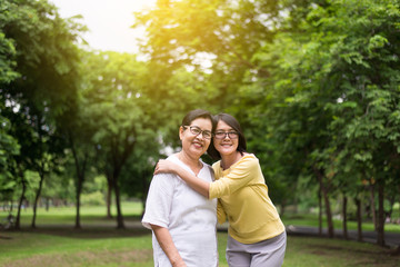 Fototapeta premium Portrait of middle aged asian female with daughter standing and hugging together outdoor,Happy and smiling,Positive thinking,Take care and support concept