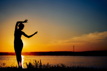Fototapeta premium girl dancing on the beach in the setting sun. silhouette image.