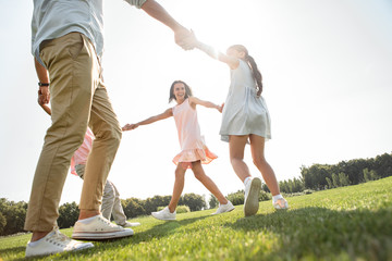 Dancing together. Happy family holding hands and dancing in the circle on the grass while spending time together outdoors