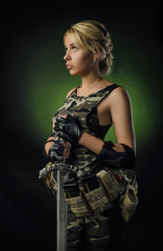 the girl in military overalls airsoft posing with a gun in his hands on a dark background in the haze