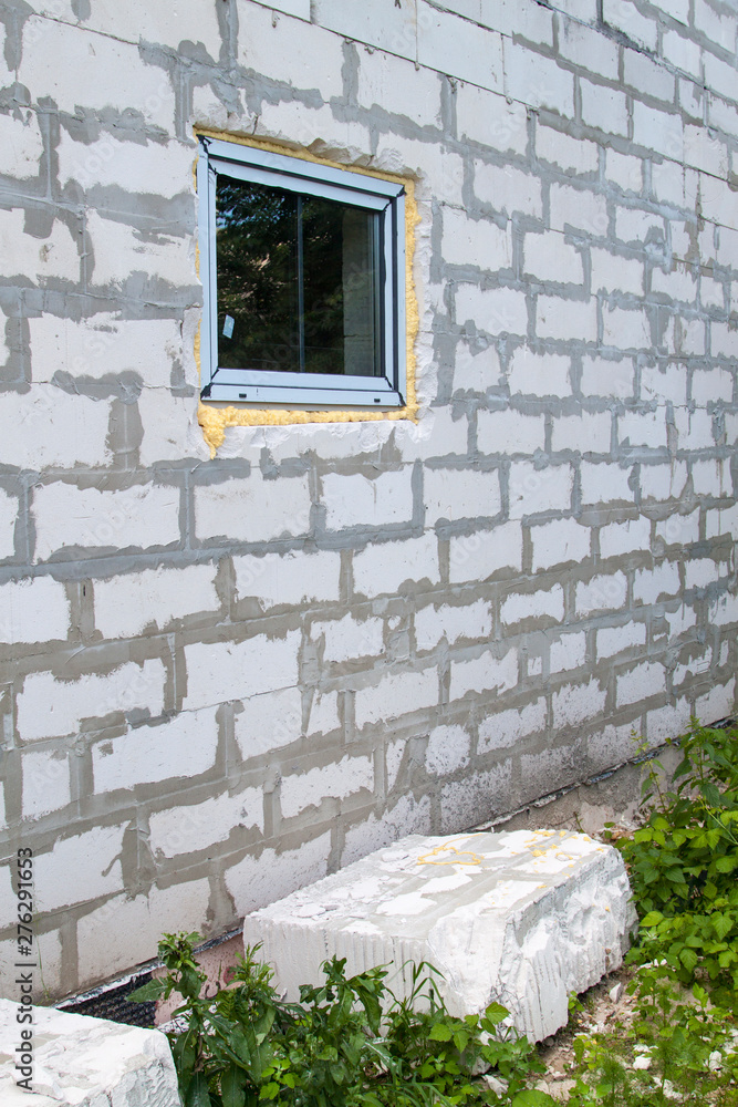 Poster facade of cottage under construction with new inserted window. block of foam concrete blocks sawn fr