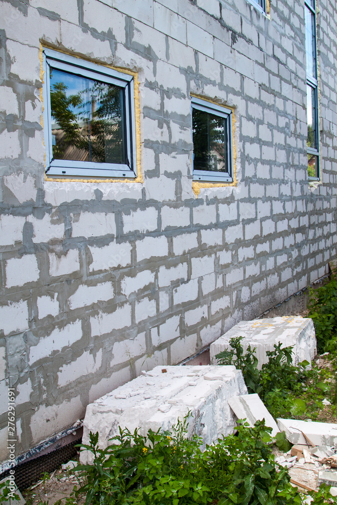 Poster facade of cottage under construction with new inserted windows. blocks of foam concrete blocks sawn 