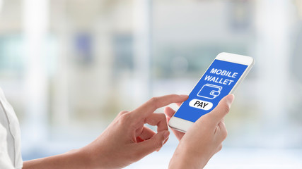 Woman hands holding and using smartphone with payment screen, wallet icon and pay button on blurred restaurant interior background. Mobile payment concept.