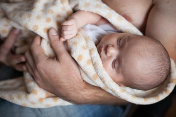 Young father holding his sweet adorable sleeping newborn child