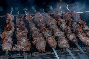 Meat as grilled shashlik or barbecue on steel sticks or shampurs  is being cooked or grilled with smoke
