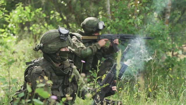 Soldier in camouflage fires a grenade launcher in assault rifle, military action in forest, soldiers on mission.