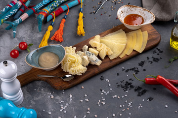 different sliced cheese is on a wooden plate with sauces