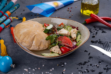 Greek salad with fresh cherry tomatoes, feta cheese, black olives, basil and onion on black stone background, pancake, top view