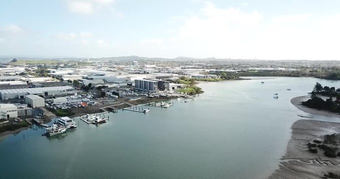 aerial 4K, flying forward slowly, view of Auckland suburbs and boat factory on coastline