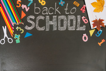 Back to school concept. School and office supplies on blackboard background. Flat lay with copy space.