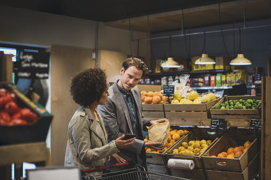 Couple late night grocery shopping and using smartphone