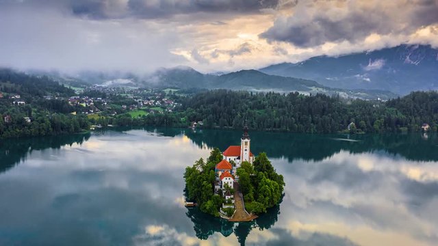Lake Bled, Slovenia - 4K aerial time-lapse (hyperlapse) footage of flying around of Pilgrimage Church of the Assumption of Maria with morning clouds above Lake Bled (Blejsko Jezero) on summer morning