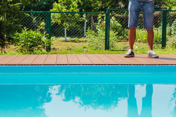 men's legs in shorts about turquoise private pool
