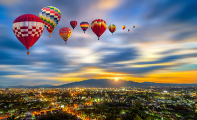 Colorful hot-air balloons flying over Chiang Mai City twilight with mountain at Dot Inthanon background in Chiang Mai, Thailand.
