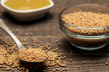 Mustard. mustard sauce in a bowl and dry mustard seeds on a brown wooden table. close-up
