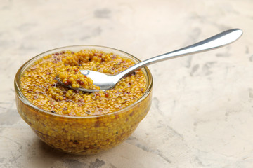 Mustard sauce, French Mustard in a bowl on a light concrete table. close-up.