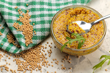Mustard sauce, French Mustard in a bowl and dry grains on a light concrete table. close-up.
