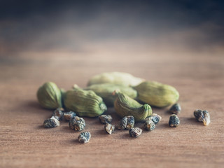Still life with cardamom seeds and green pods on blur background, closeup.
