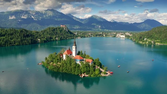 Lake Bled, Slovenia - 4K aerial footage of flying around Pilgrimage Church of the Assumption of Maria above Lake Bled (Blejsko Jezero) on a beautiful summer day with blue sky and clouds