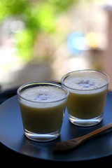 Two glasses of refreshing mango lassi drink, decorated with cardamom. Selective focus.