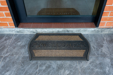 Front door with doormat plants with welcome written on it, welcome mat at home.