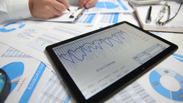 Businessman working with tablet pc, calculating, reading and writing reports. Office employee, table closeup. Business financial accounting concept.