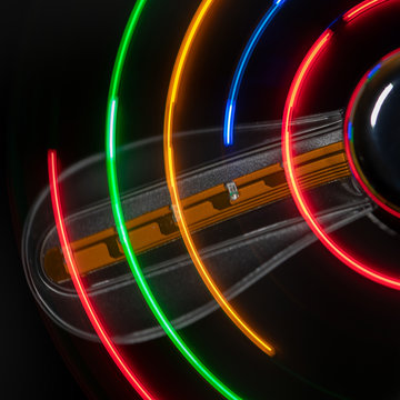 Ein Propellerfl&uuml;gel mit unterbrochenen roten, orangen, gr&uuml;nen und blauen unterbrochenen Linien halbkreisf&ouml;rmig vor schwarzem Hintergrund