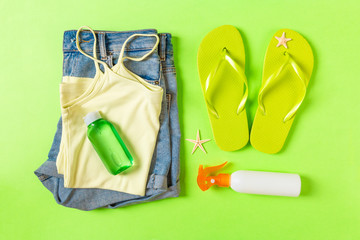 Flat lay composition with green Beach accessories on green color background. Summer holiday background. Vacation and travel items top view