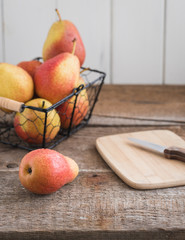 Fresh pears in the basket on the wooden background