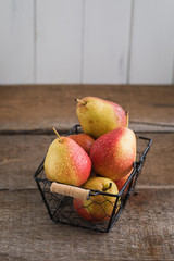Fresh pears in the basket on the wooden background