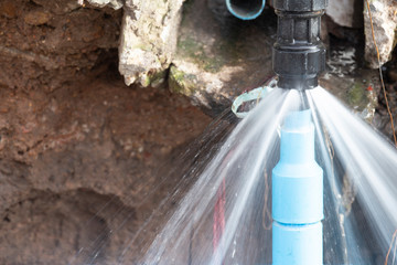Water pipe break .Exposing a burst water main, focused on the spraying water and the pipe.