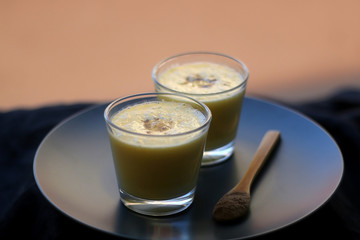 Two glasses of refreshing mango lassi drink, decorated with cardamom. Selective focus.