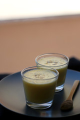 Two glasses of refreshing mango lassi drink, decorated with cardamom. Selective focus.