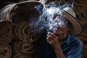 Old man smoking cigarette and the smoke released from the mouth, Bad habits concept..