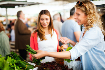 Young women friends baying vegetables and fruits on the market