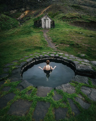 Back view of woman in outdoor bath near old ground house. - obrazy, fototapety, plakaty