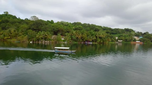 Motor boat on the lake de atitlan, view of flores ciudad. Forest in the background.