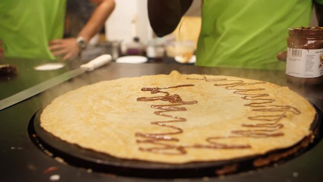 Cook drizzling hazelnut spread onto a freshly made crepe