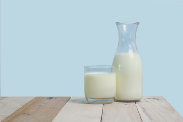 A bottle of rustic milk and glass of milk on a wooden table