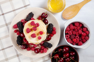 Top view Pancakes with honey syrup and berry for breakfast. Food for breakfast. Copy space for design. homemade american pancakes snack. Flat lay of sweet cherry, blackberry, raspberry and pancake