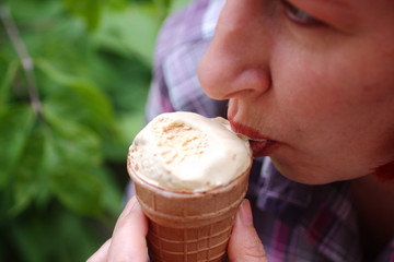 The girl is happy to eat ice cream in a waffle Cup.