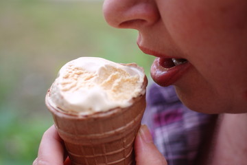 A girl in extreme heat eating ice cream in a waffle Cup.